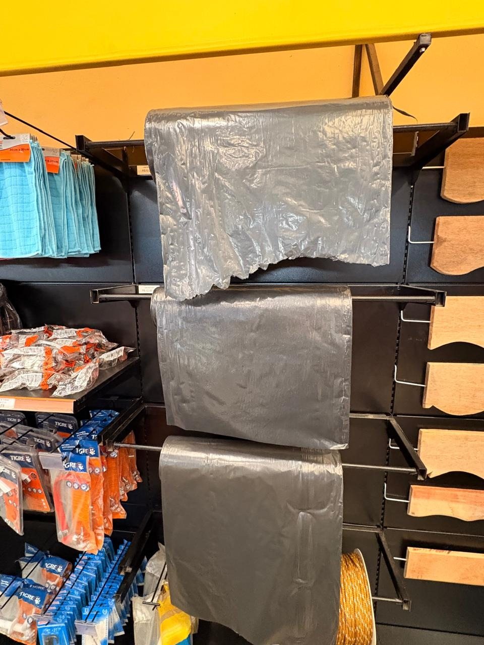 Lonas plásticas pretas organizadas na prateleira da loja